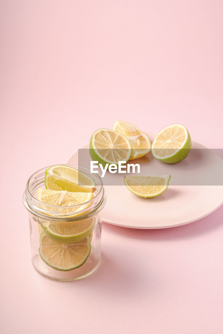 Fresh tasty lemon and lime citrus fruits slices on pink background