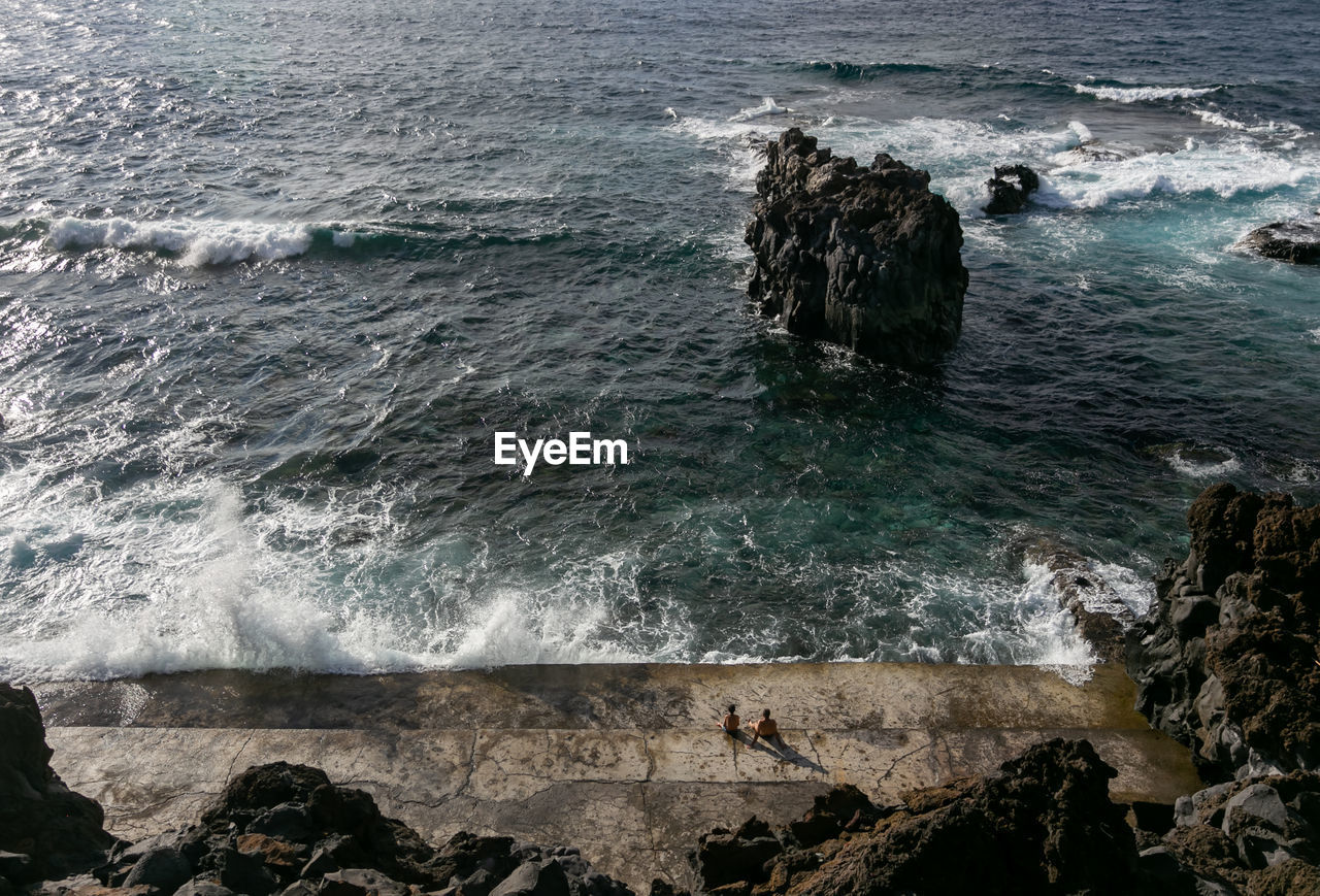 HIGH ANGLE VIEW OF ROCKS ON SEA