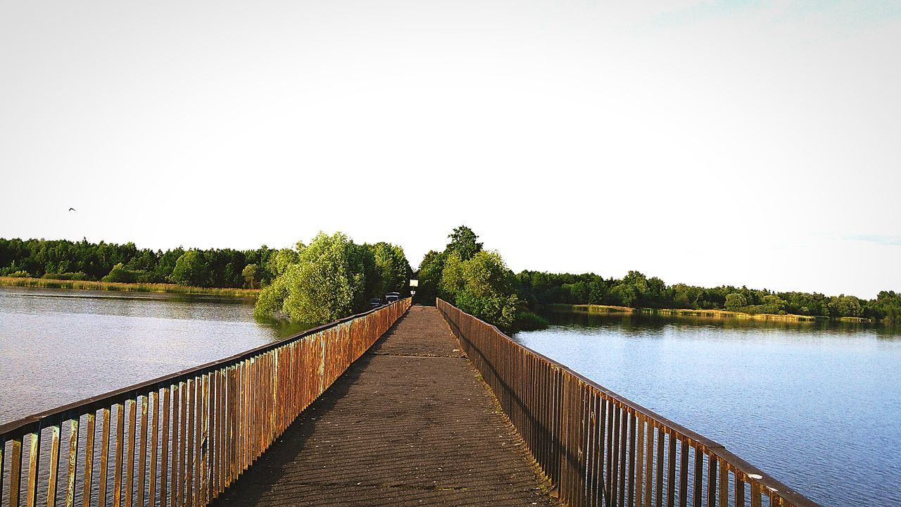 Footbridge over river against clear sky