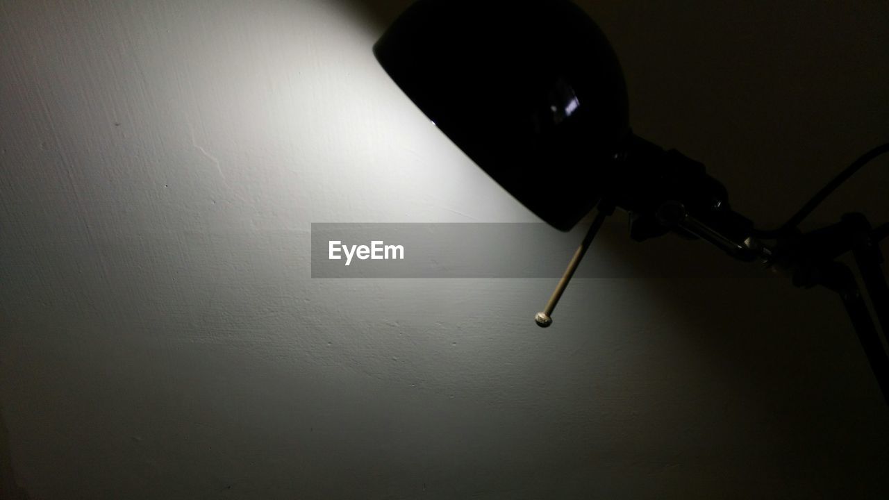 CLOSE-UP OF ELECTRIC LAMP ON TABLE AGAINST WALL