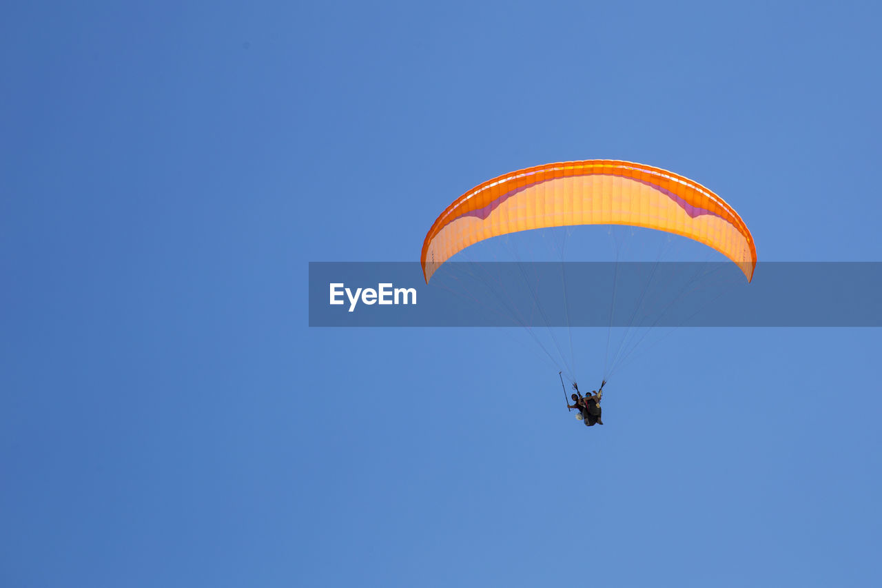 Low angle view of person paragliding against clear blue sky