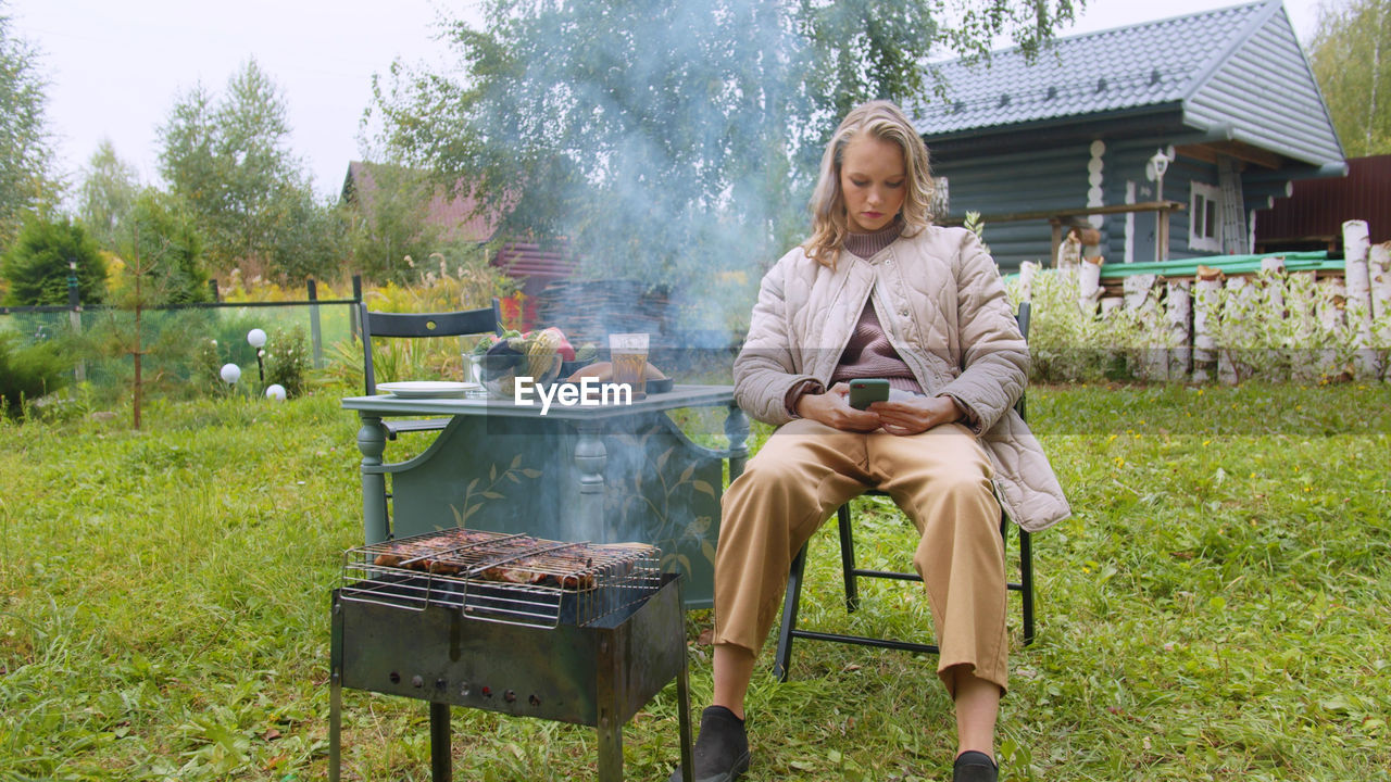 Woman using mobile phone while preparing food at yard