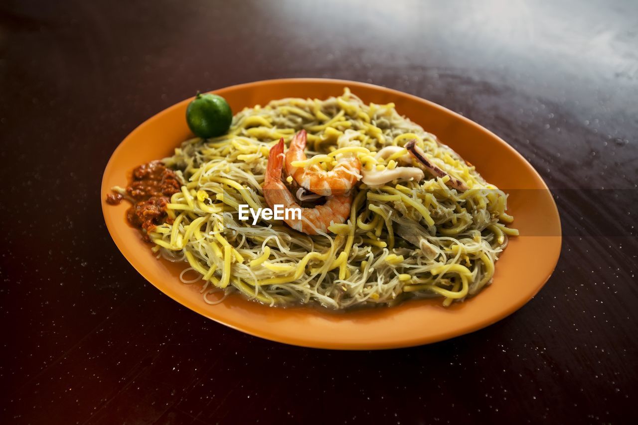 High angle view of noodles and prawns served in plate on table