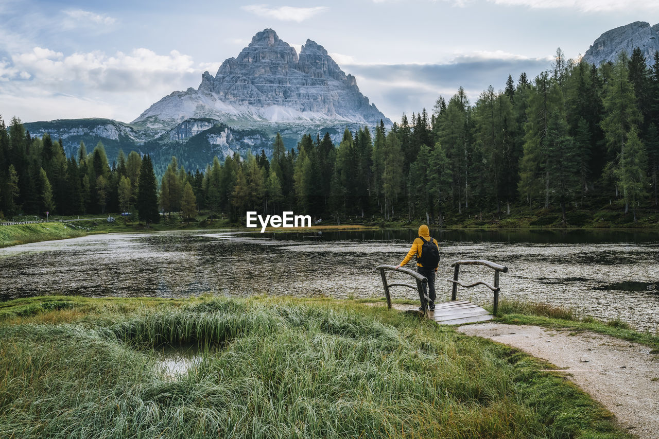 MAN STANDING BY PLANTS AGAINST MOUNTAIN RANGE