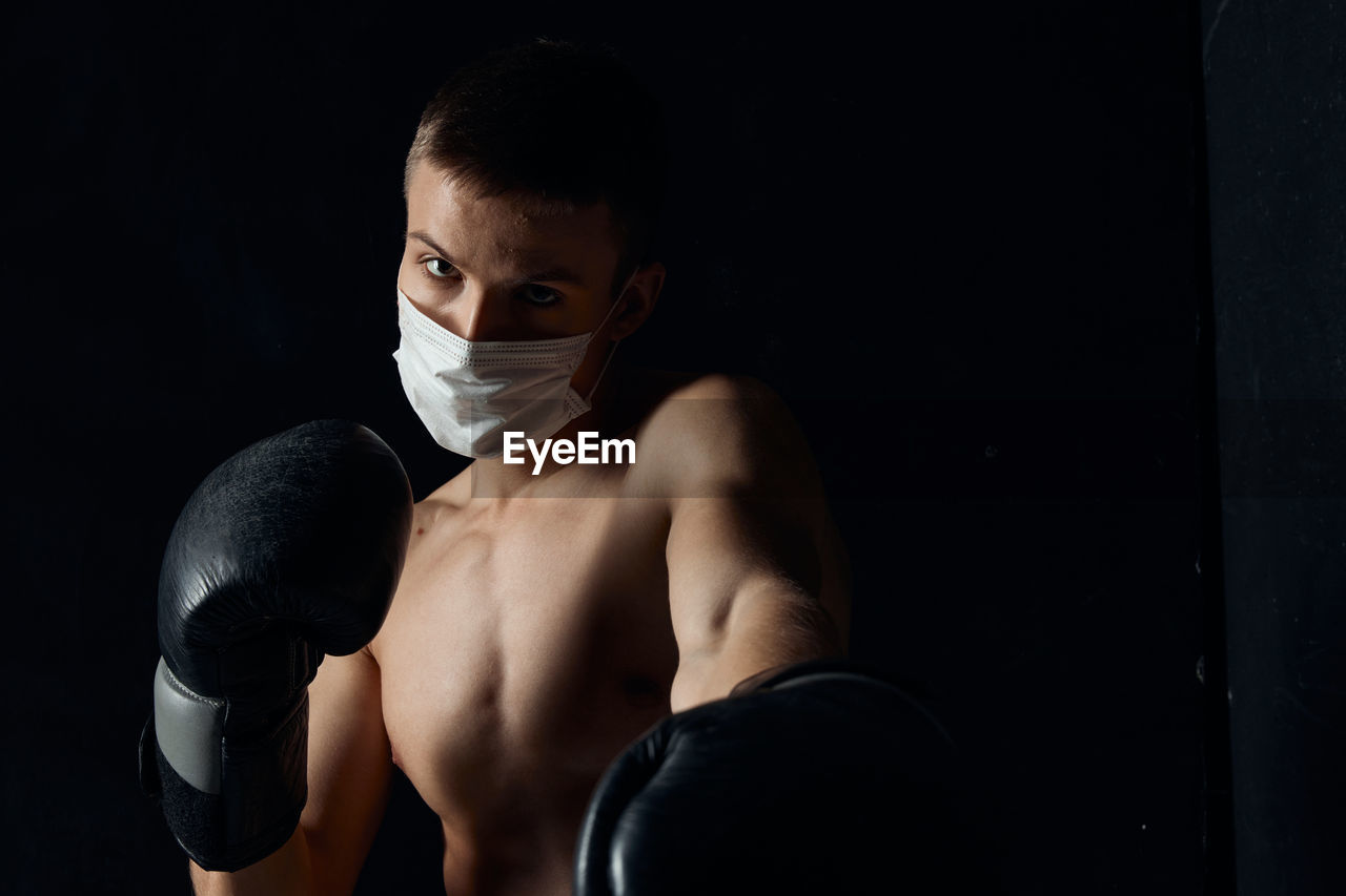 Portrait of shirtless man against black background