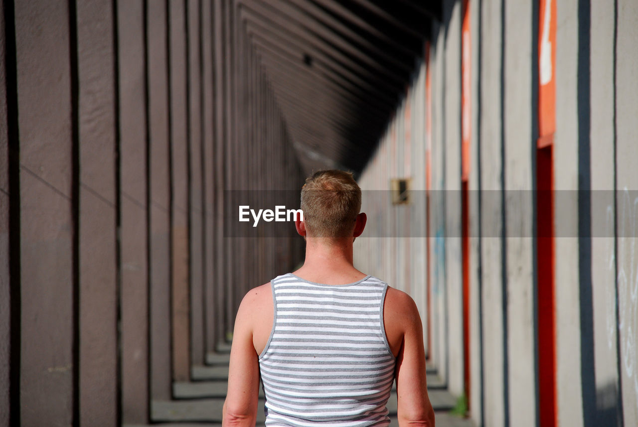 Rear view of man standing in building corridor