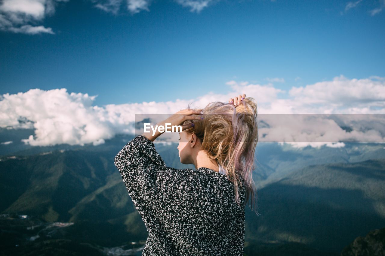 Woman tying hair against mountains