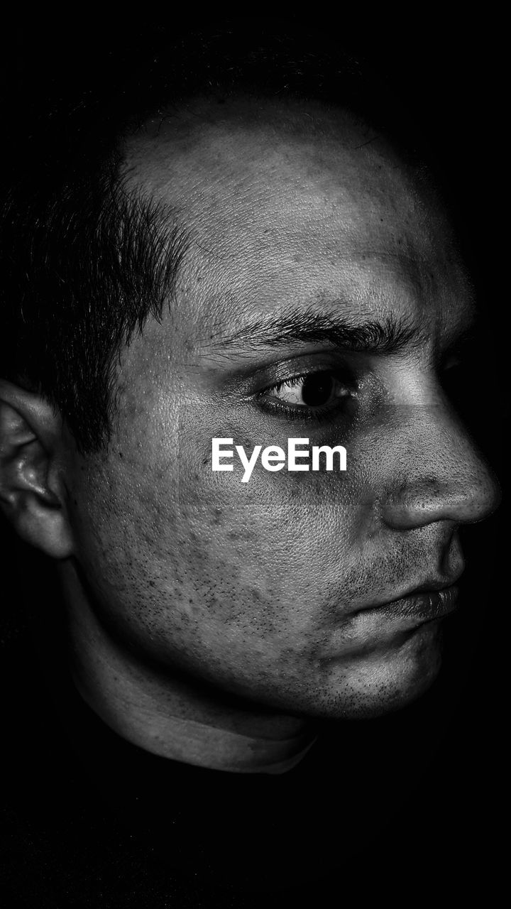 Close-up of thoughtful man against black background