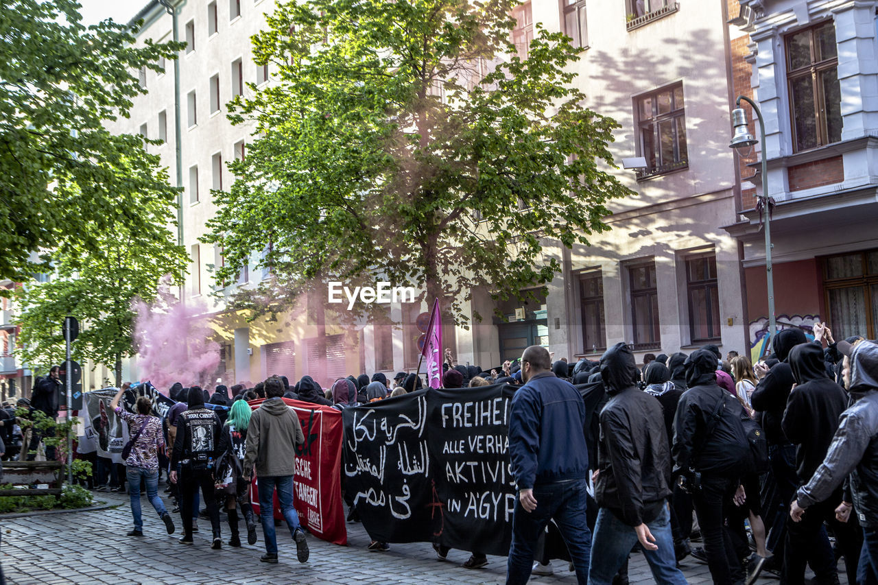 Crowd walking on street by buildings at may day