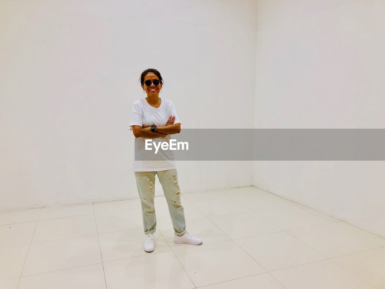 Portrait of smiling woman standing on floor against white wall