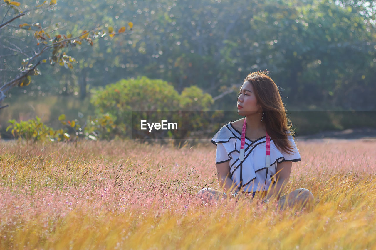 Woman sitting on field against sky