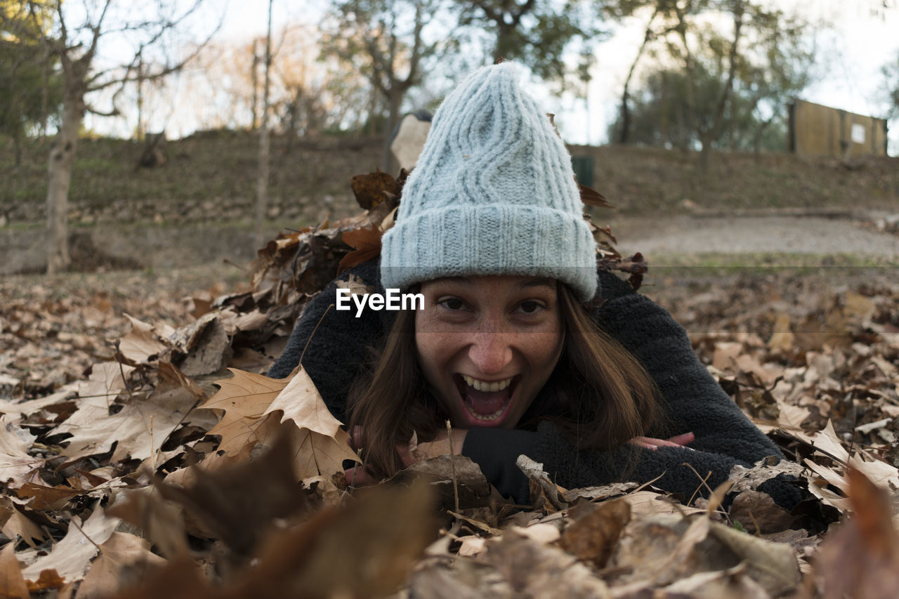 Portrait of excited woman lying on autumn leaves
