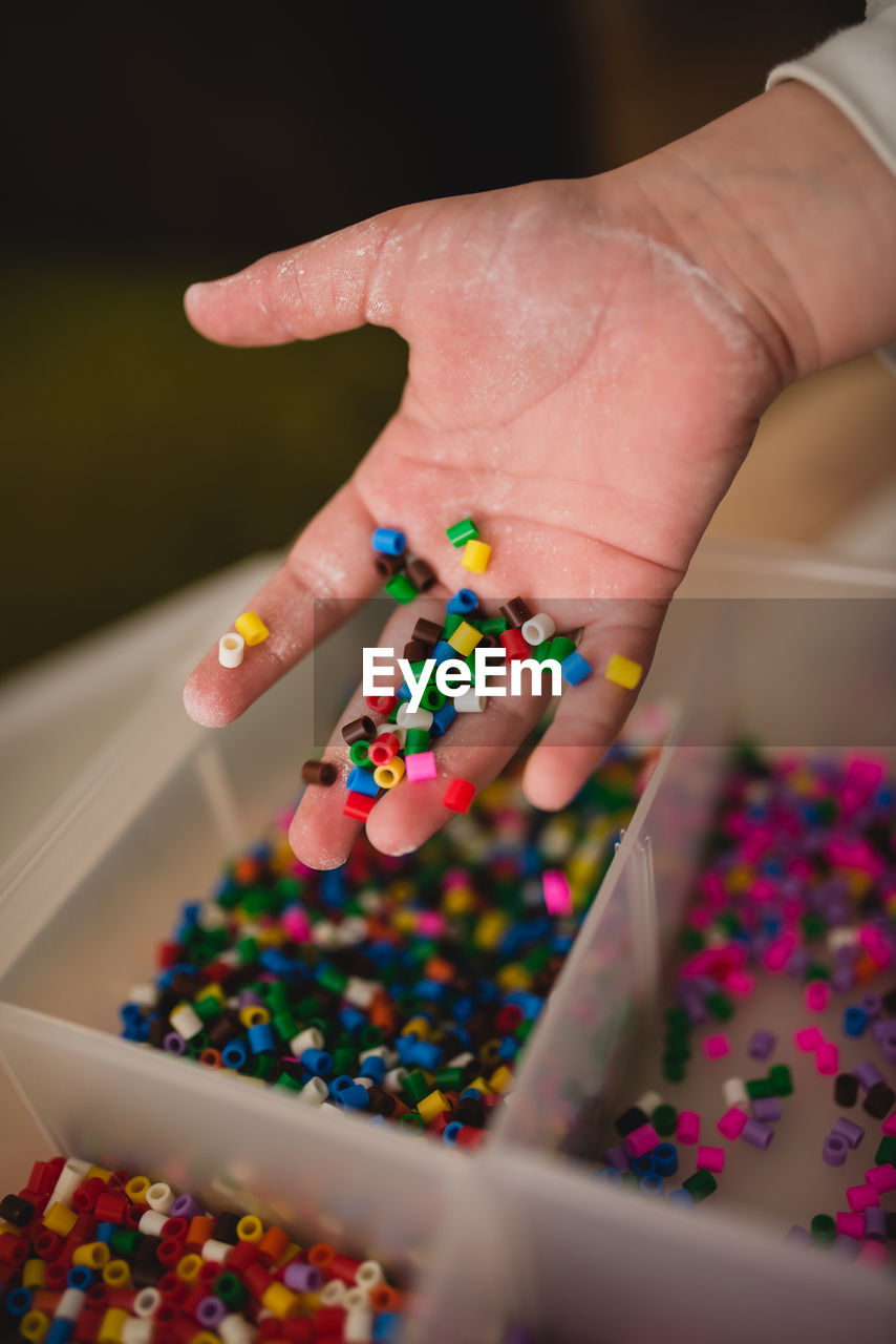 Unrecognizable child playing with colorful mosaic pieces while having fun at home