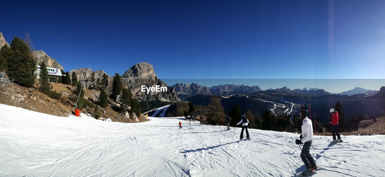 People skiing on snow covered mountains against clear sky