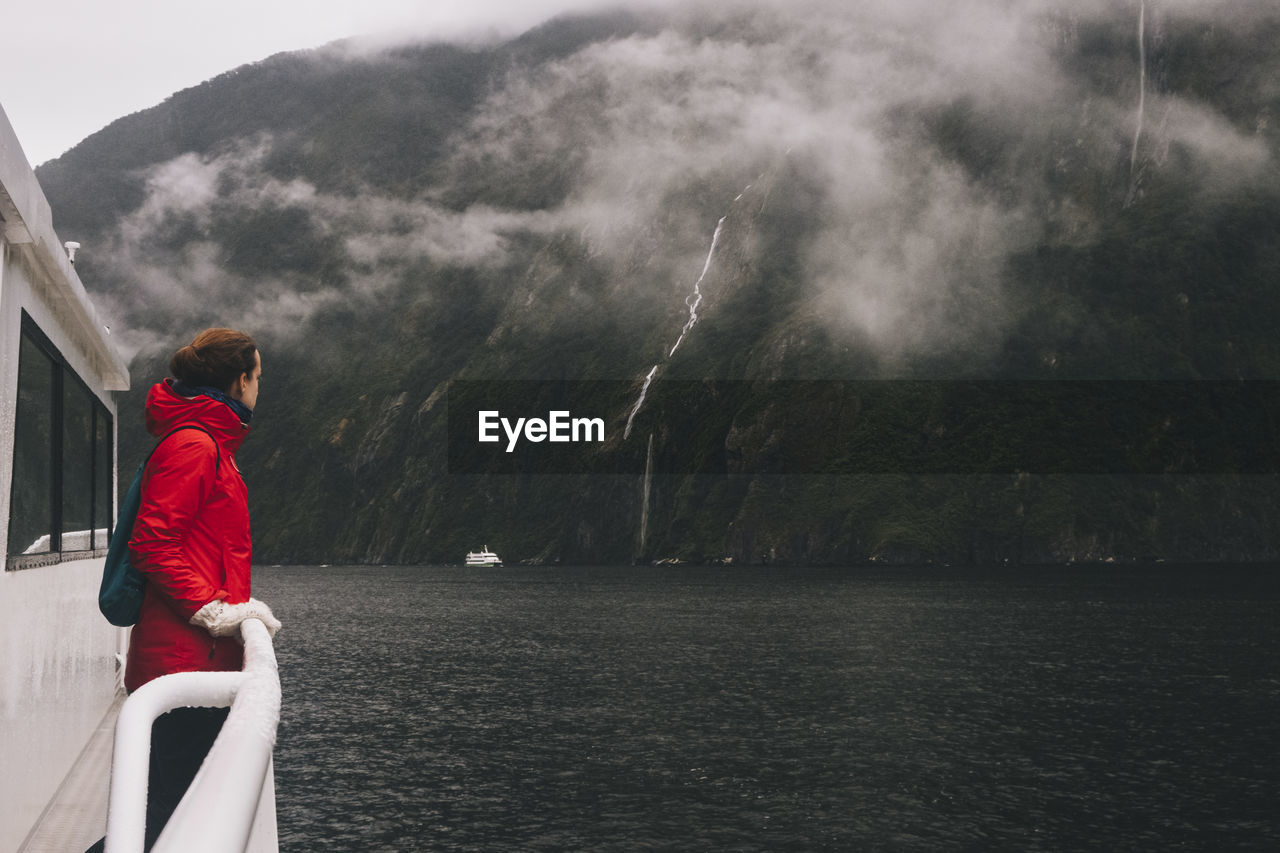 A woman stares up at the surrounding mountains in milford sound, nz