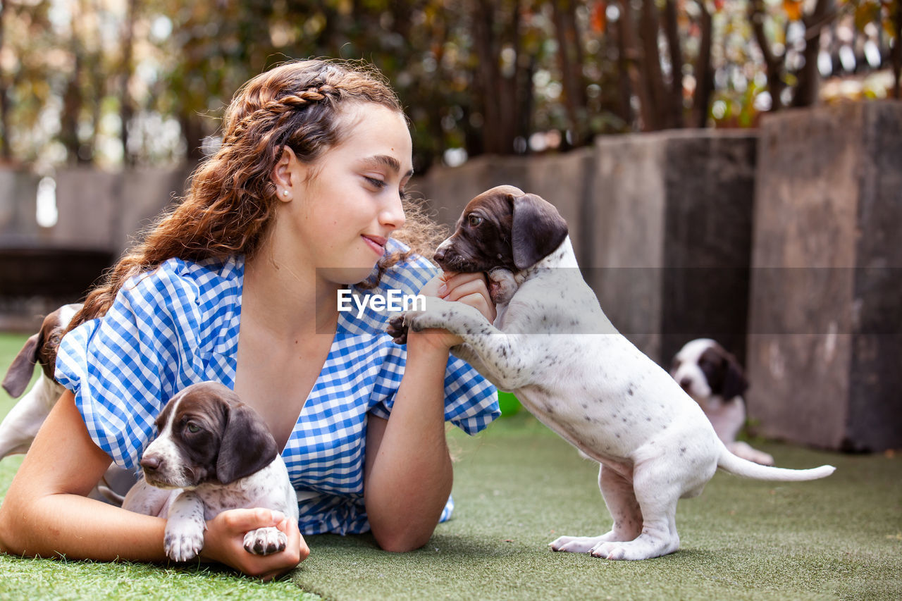 Beautiful young girl having fun with her small french braque puppies