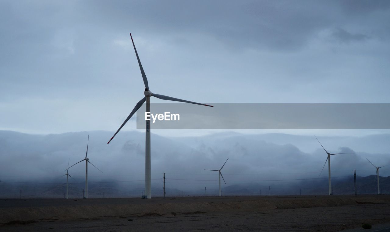 View of wind farm by foggy mountains