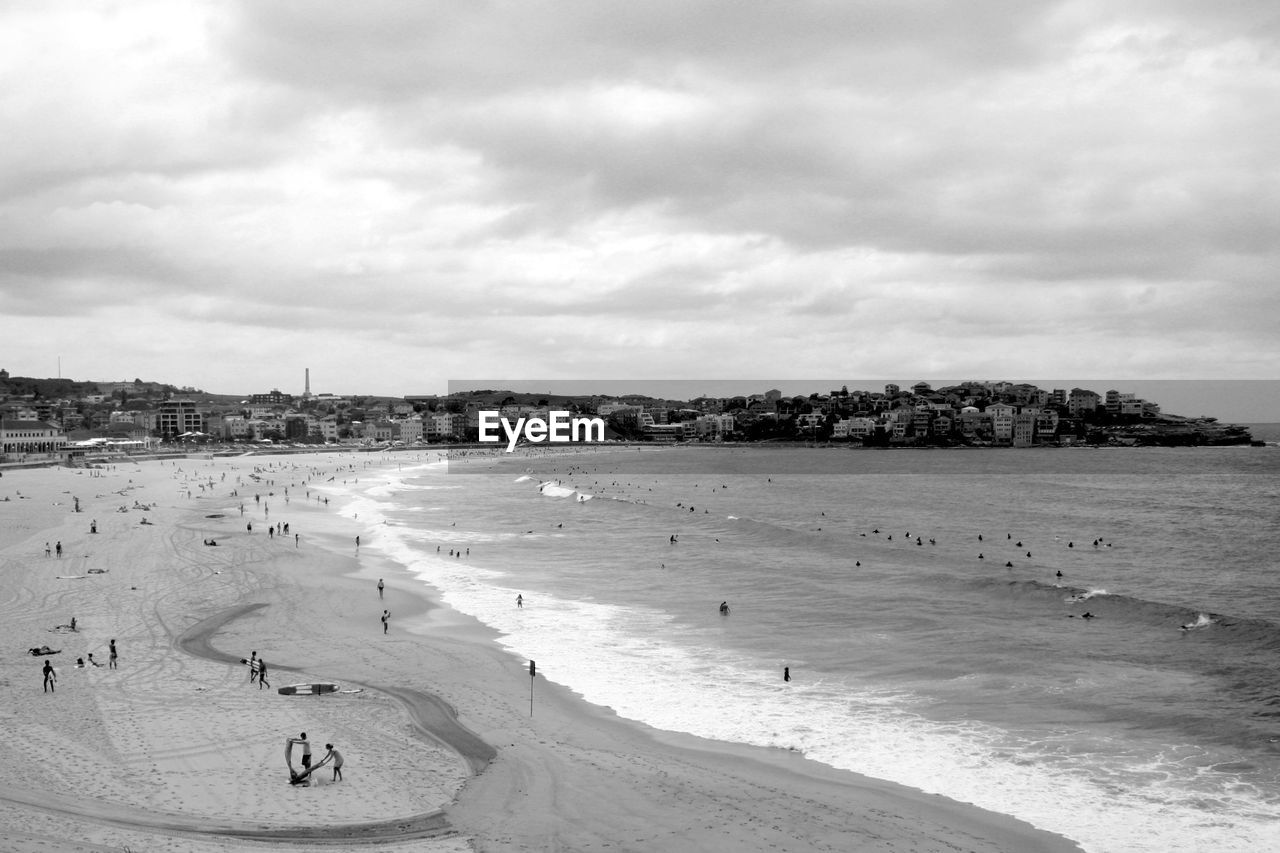 Scenic view of sea in city against cloudy sky