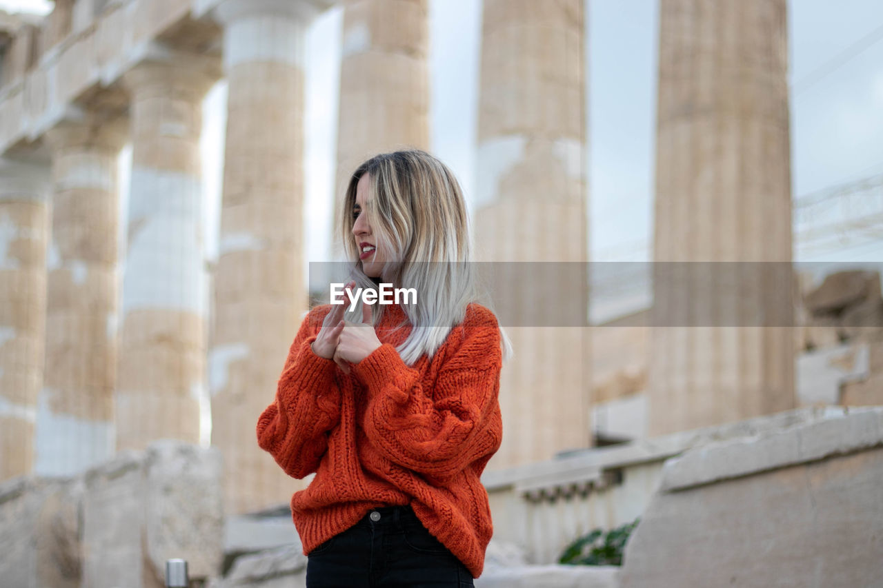Young girl with long blonde hair and a disgusted face in greece with the acropolis in the background