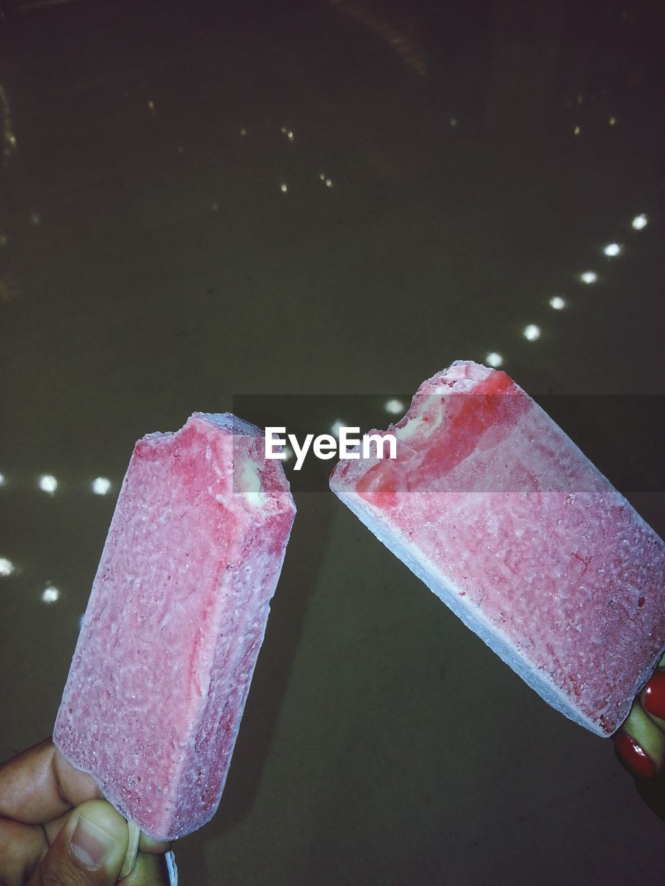 CLOSE-UP OF HAND HOLDING ICE CREAM CONE ON GLASS