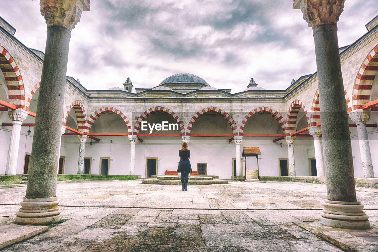 Rear view of woman standing in historic cathedral against sky