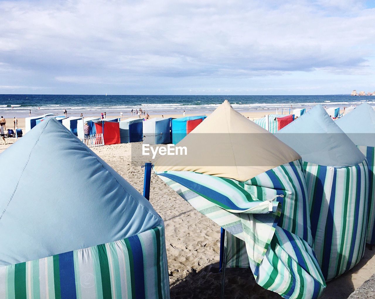 MULTI COLORED UMBRELLAS ON BEACH AGAINST SKY
