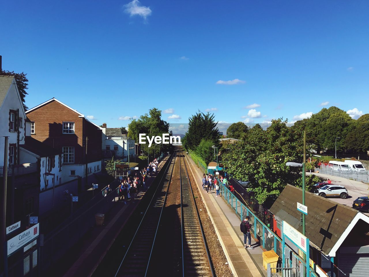 High angle view of people at railroad station in city against blue sky