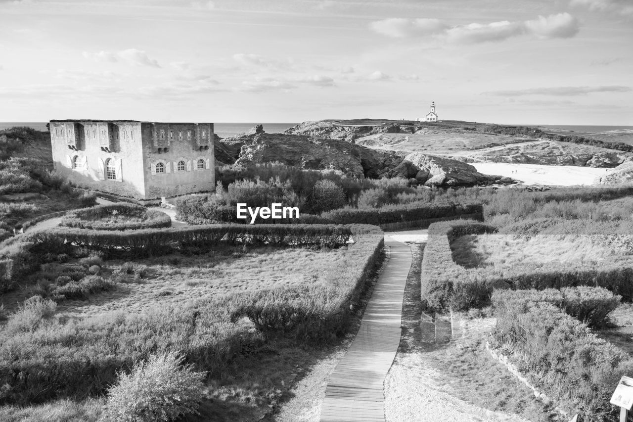 Footpath leading towards house against sky