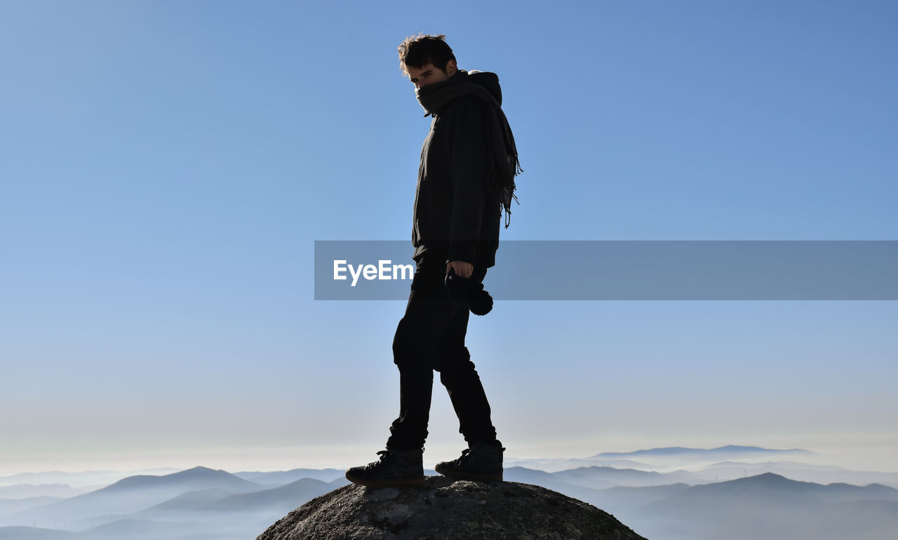 Hiker standing on mountain against sky