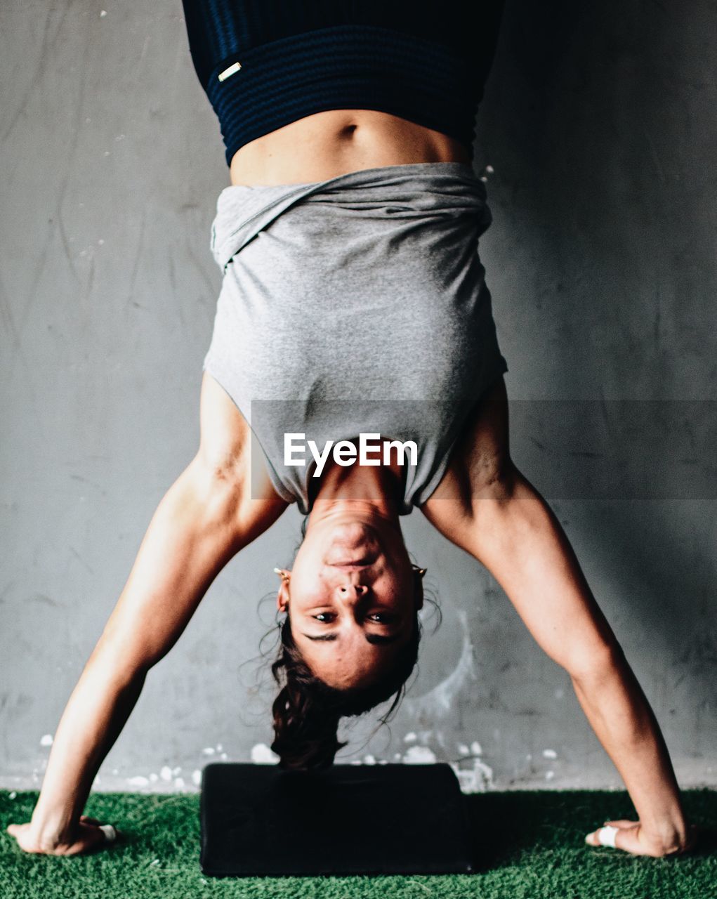 Portrait of woman doing handstand against wall
