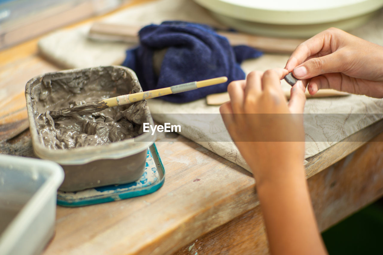 Motion blurred hands of girl molding the clay work with wet mud on plastic tray