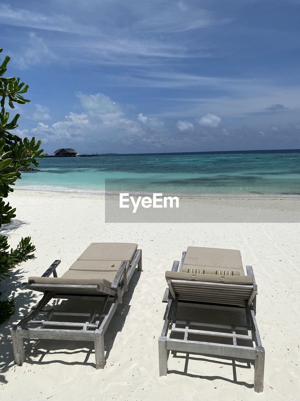 DECK CHAIRS ON BEACH AGAINST SKY