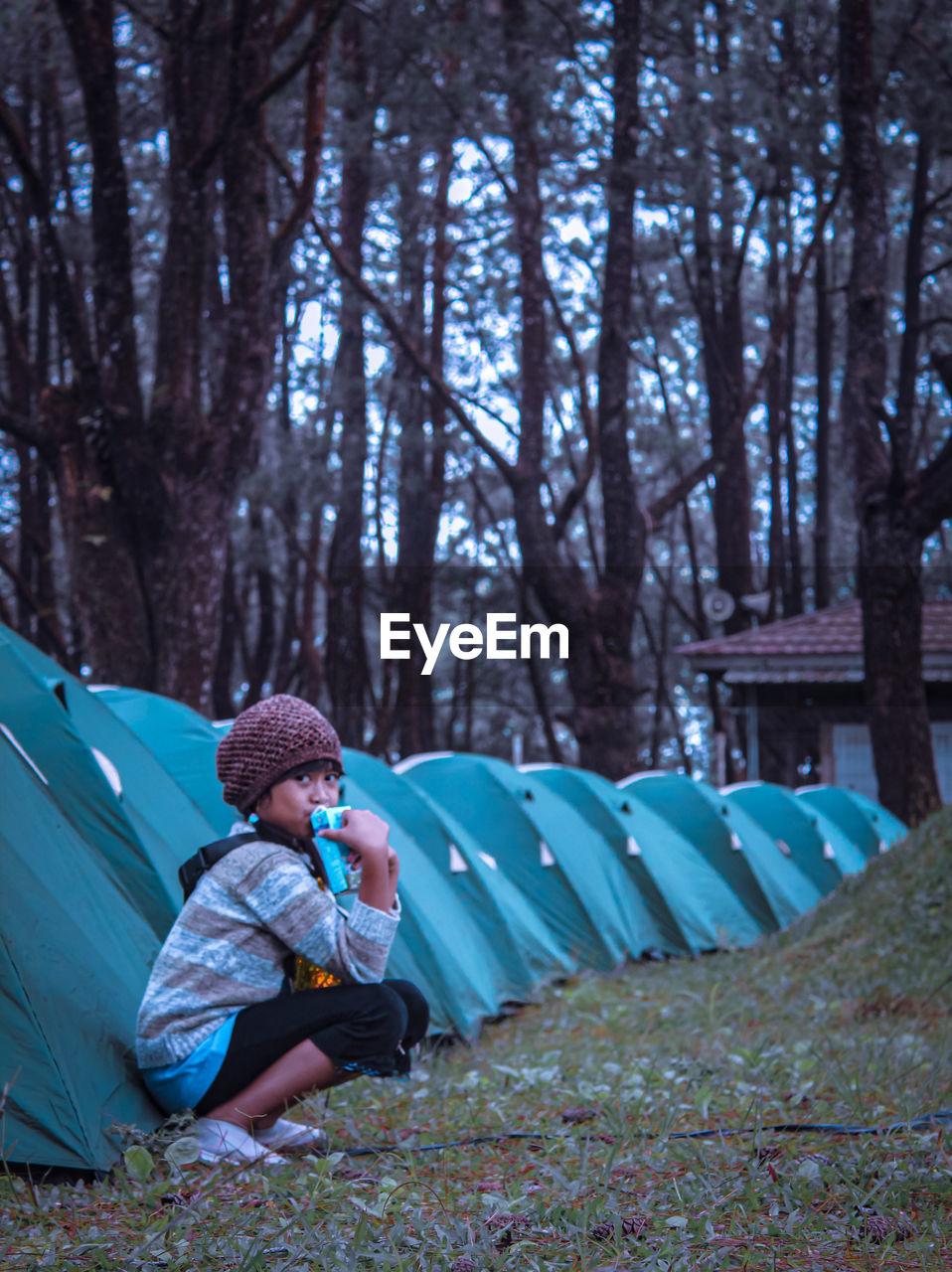 WOMAN SITTING ON TENT IN FOREST