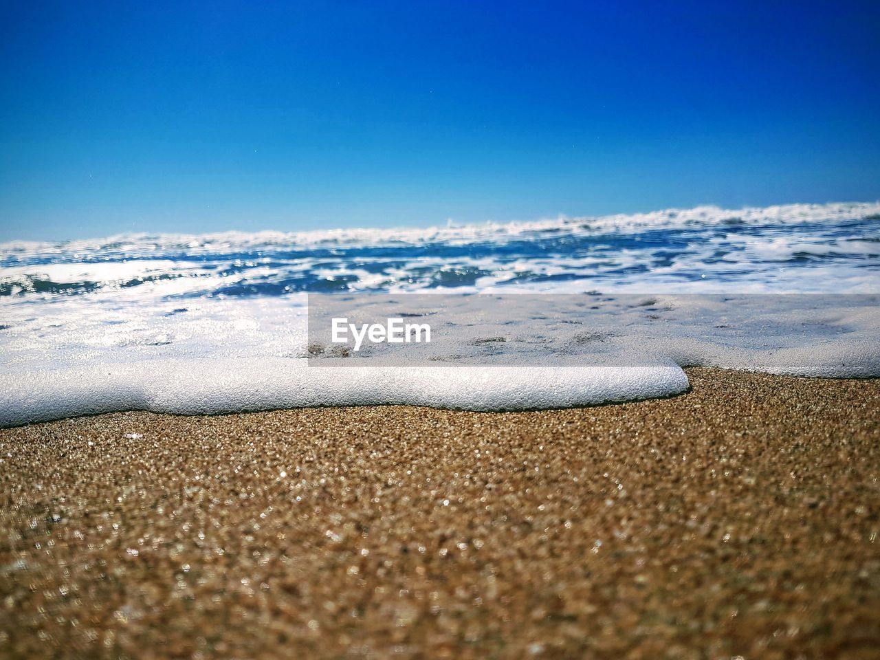 SURFACE LEVEL OF SEA SHORE AGAINST BLUE SKY