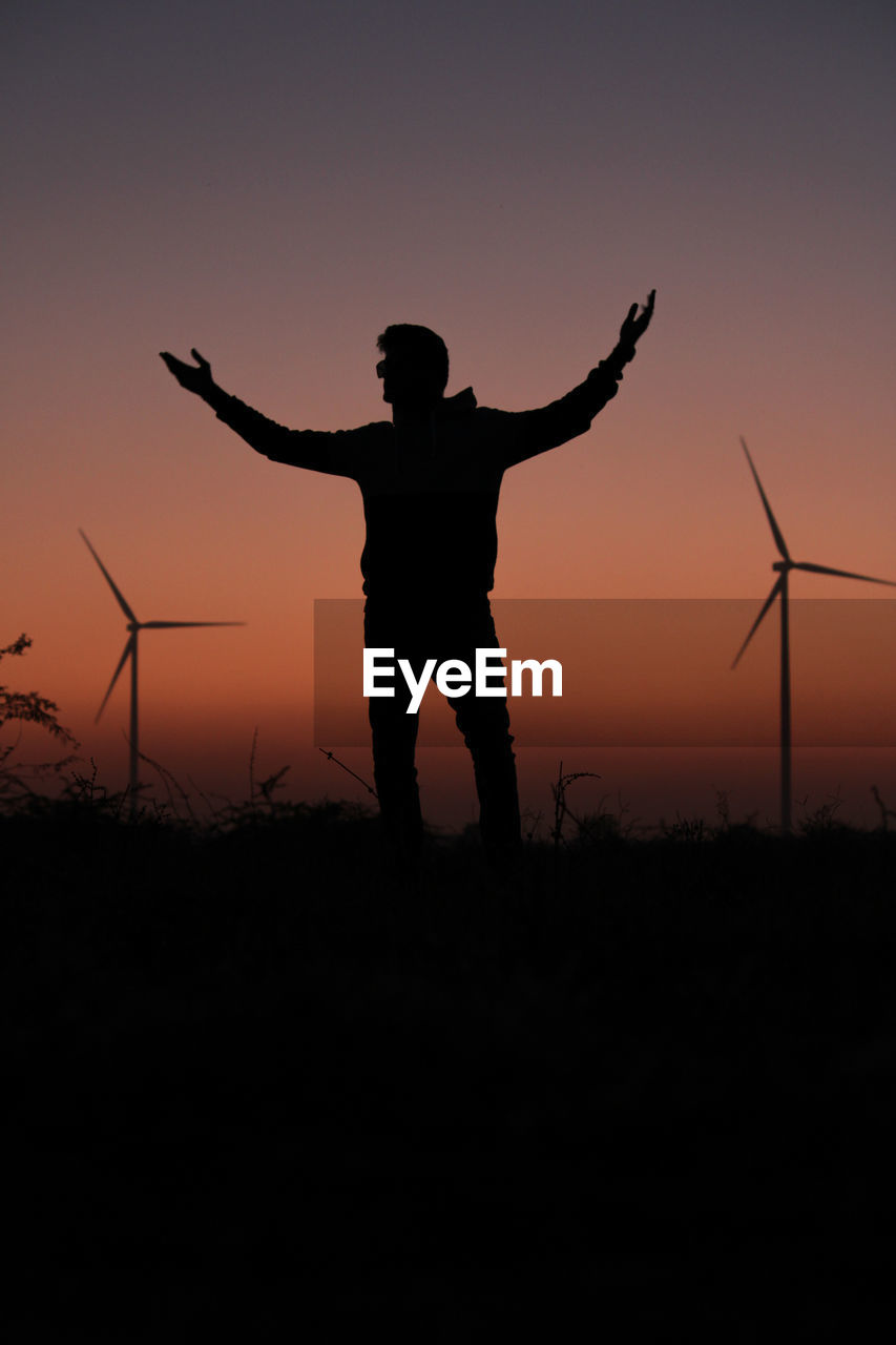 Silhouette man standing on field against sky during sunset