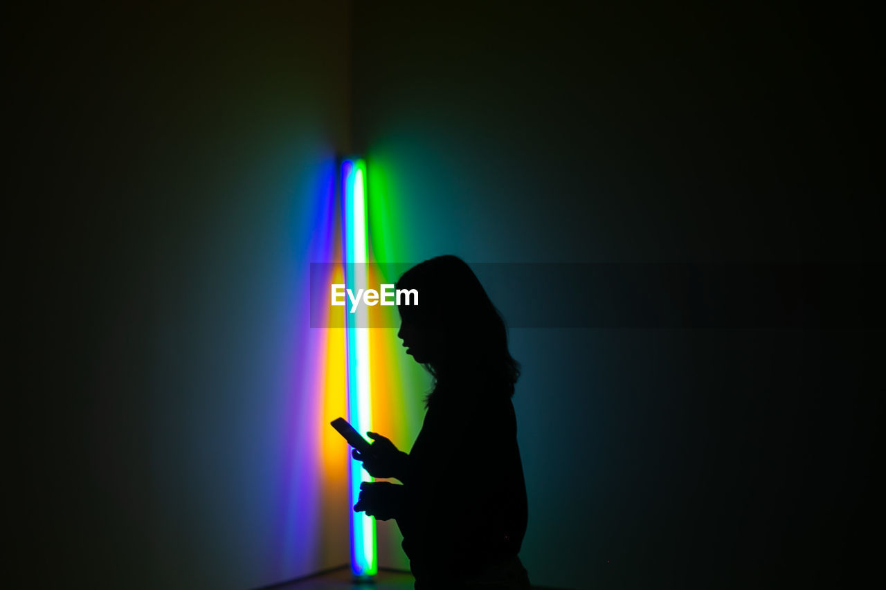 SIDE VIEW OF SILHOUETTE PERSON HOLDING SMART PHONE