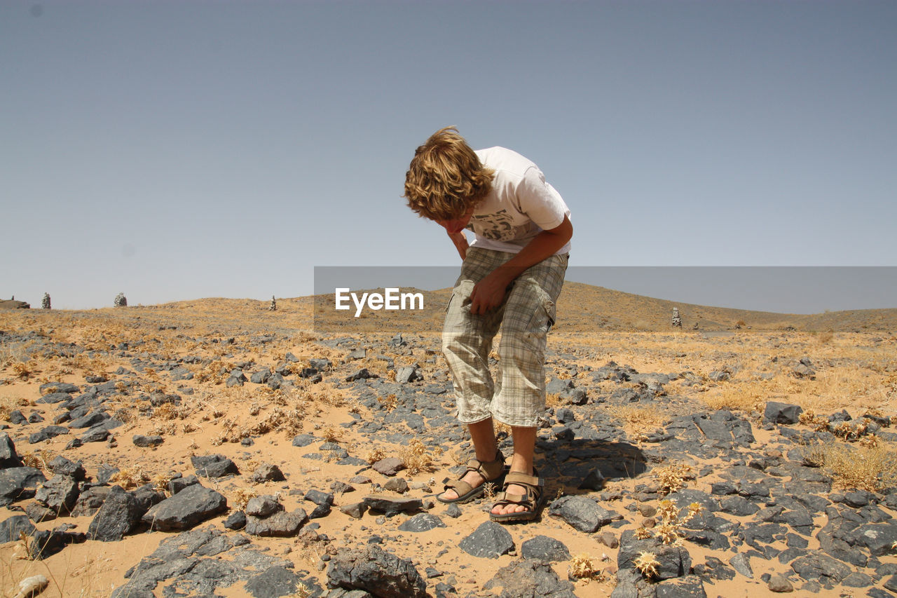 Young man looking down while standing on rocks