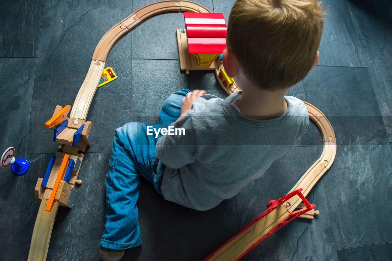 High angle view of boy playing with train set on floor at home