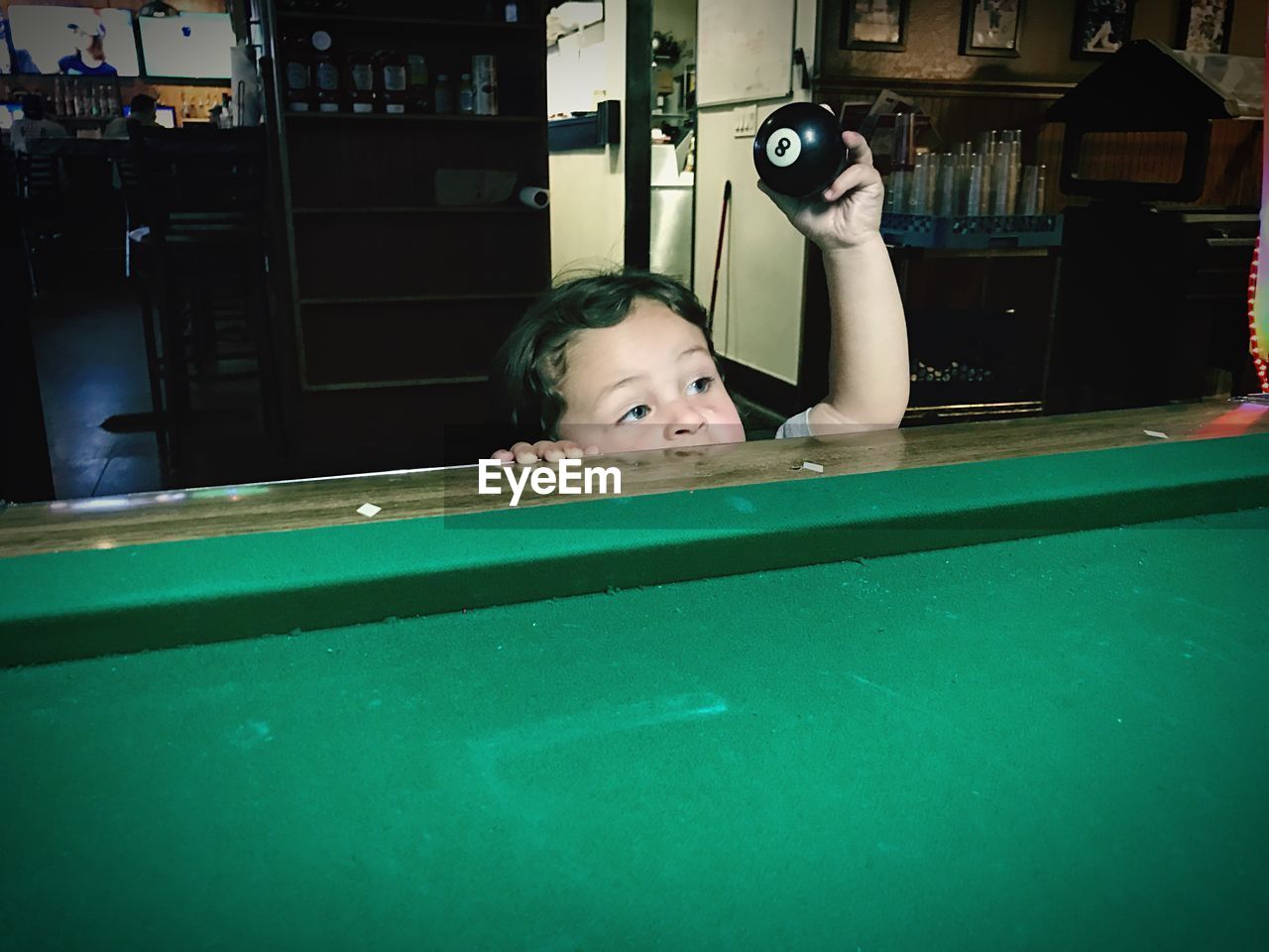 High angle view of cute boy holding pool ball by table