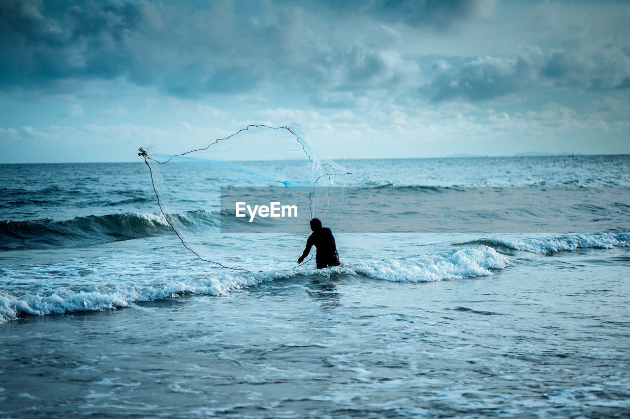 Man fishing in sea against sky