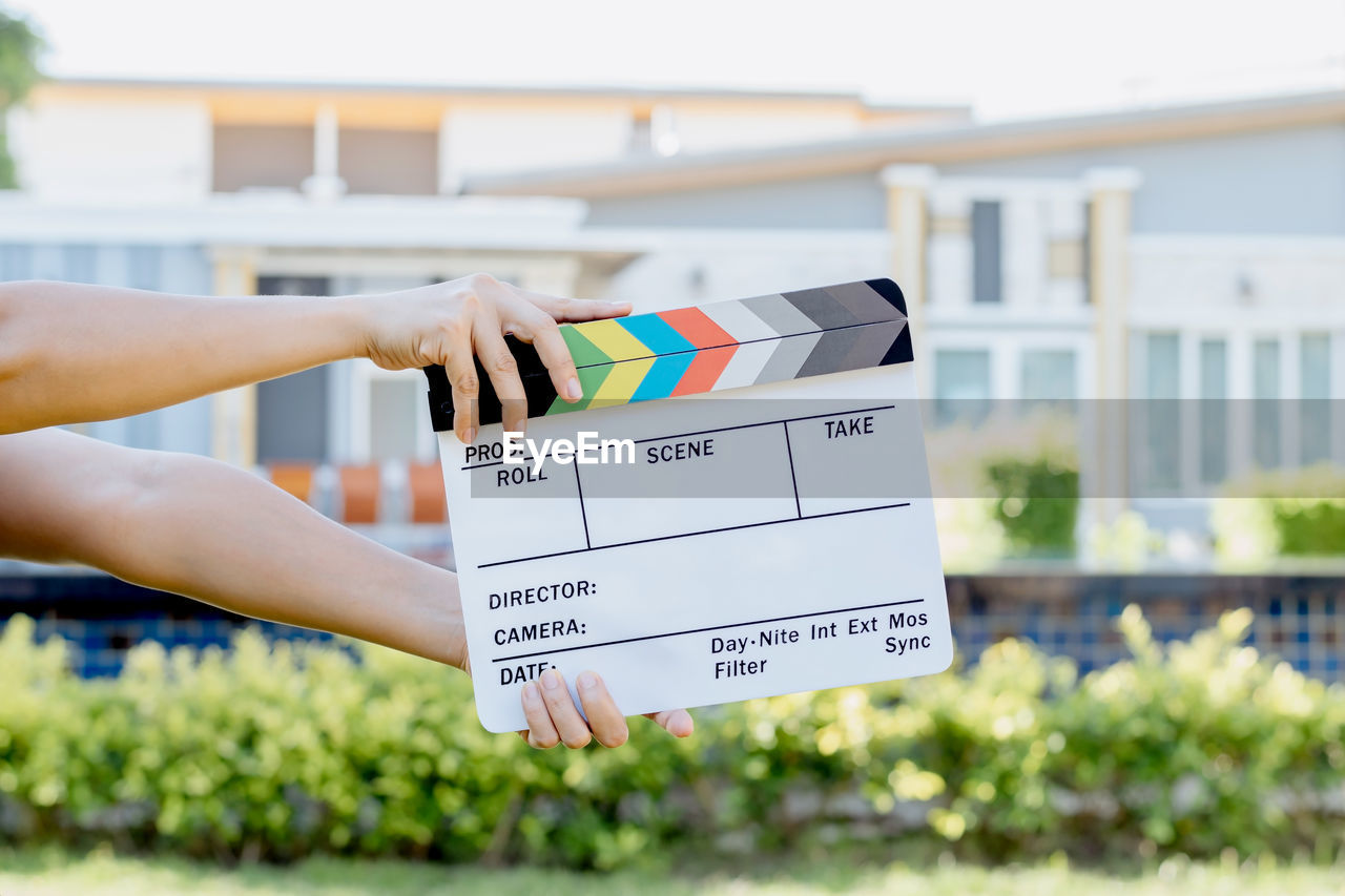 Hand holding film slate colors board for movie cinema and television industry on green background