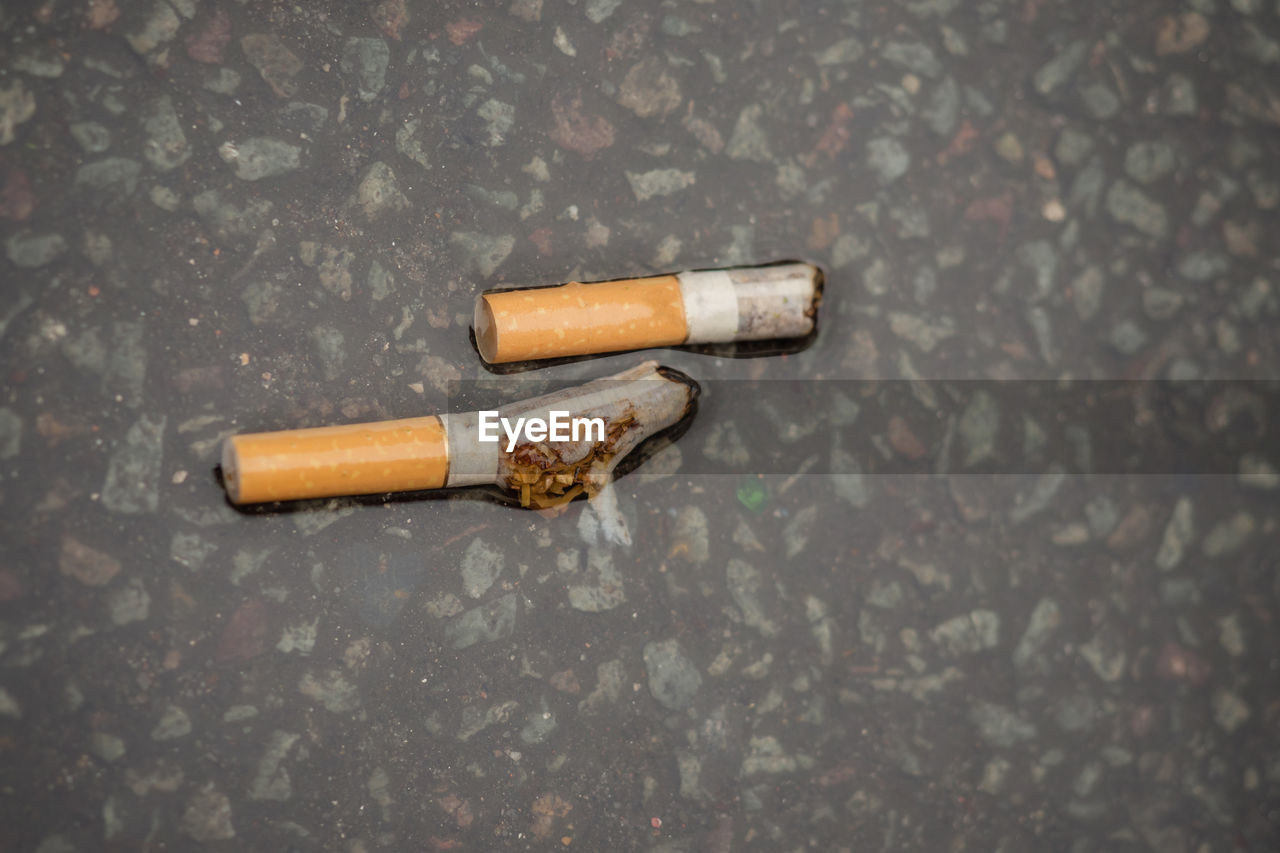 Close-up of wet cigarette on footpath