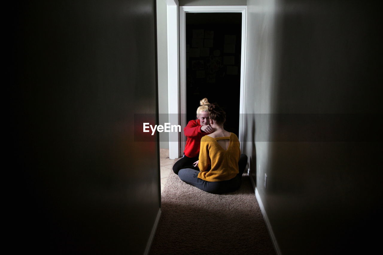 Lesbian couple sitting on rug at home