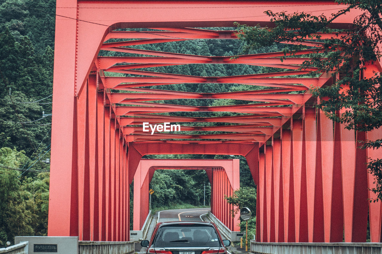 Car on red metallic bridge