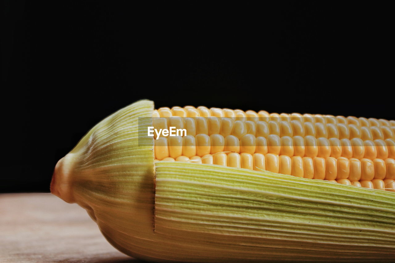 Close-up of yellow corn on table against black background