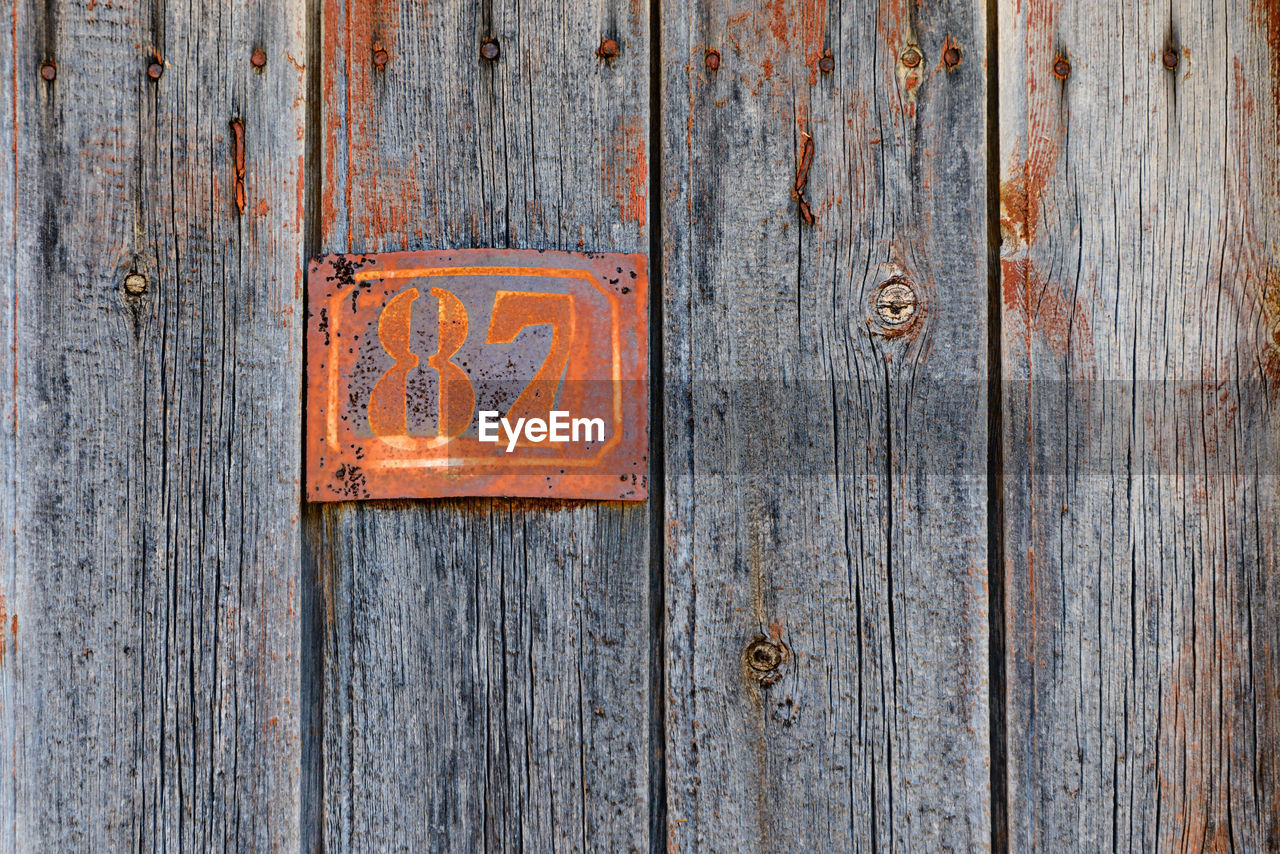 Full frame shot of old door with rusty metallic number