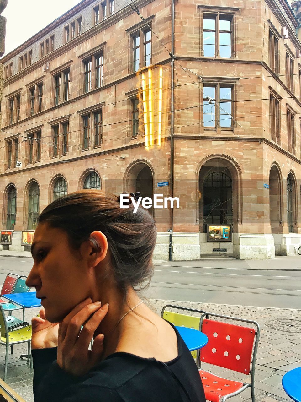 Woman sitting in cafe by glass window against building