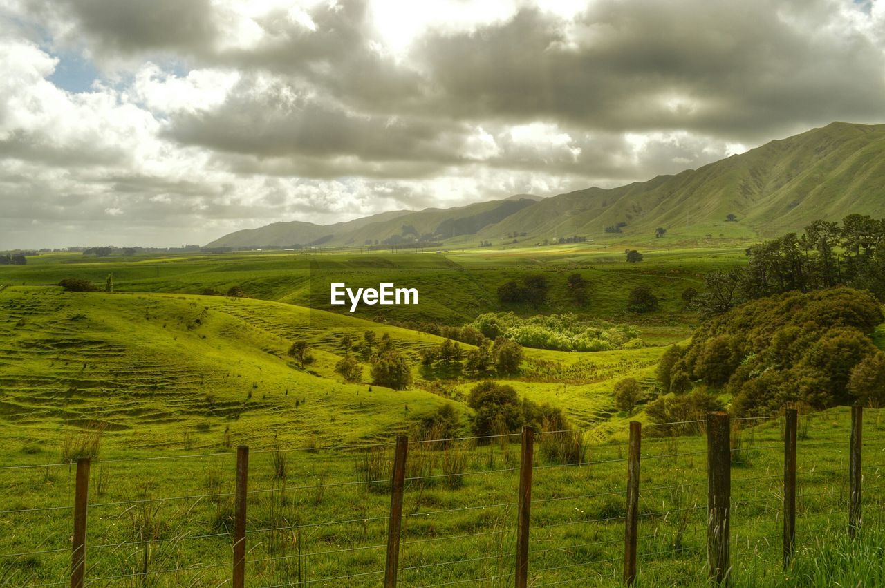 Scenic view of green landscape against cloudy sky
