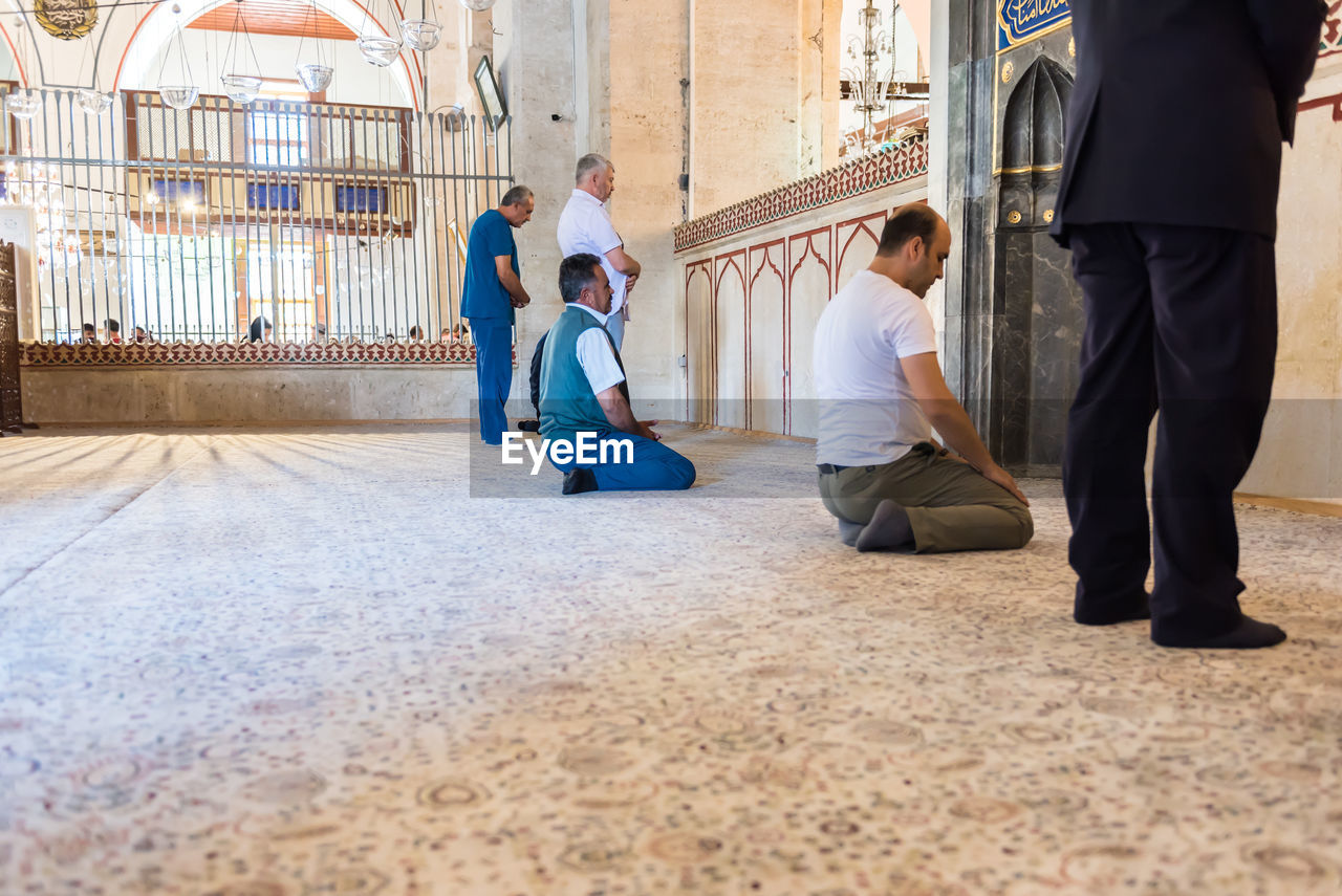 REAR VIEW OF PEOPLE SITTING ON THE FLOOR IN BACKGROUND