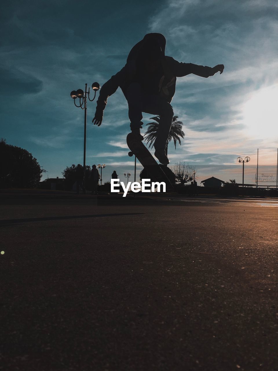 Full length of silhouette man skateboarding on footpath against sky during sunset